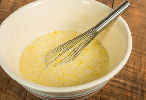 Bowl of eggs and milk with whisk